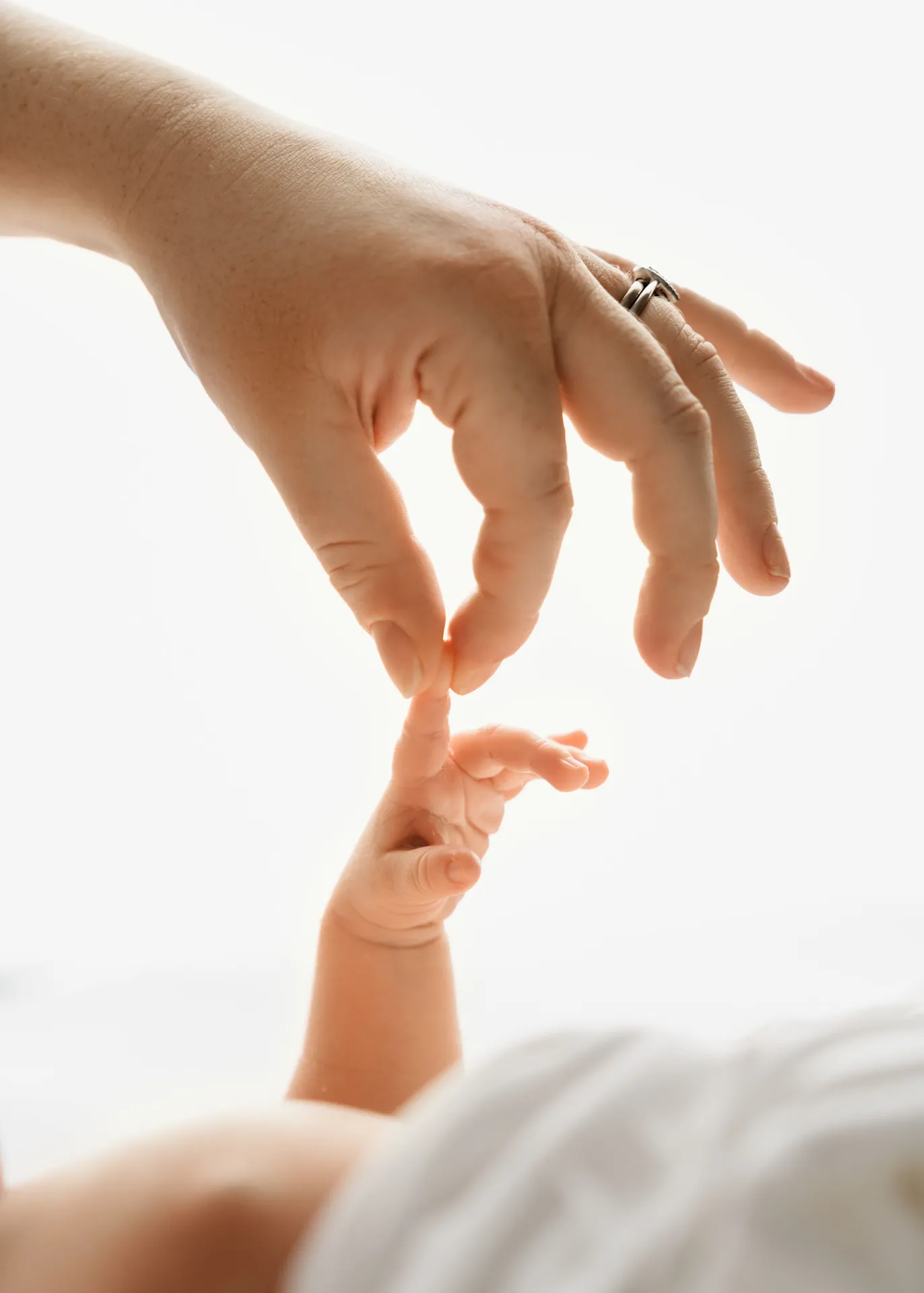 Adult hand gently touching tiny baby hand in tender moment