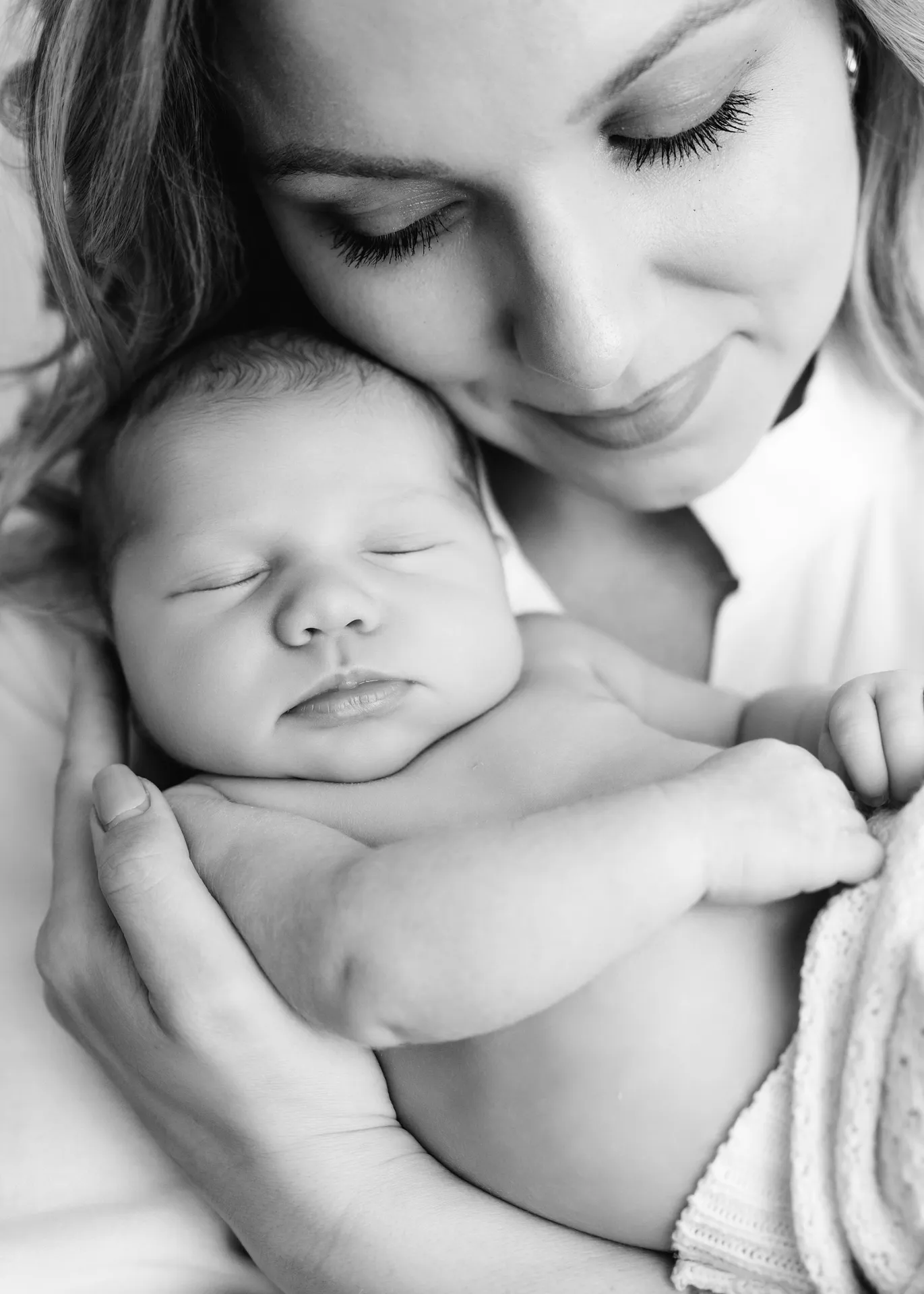 Black and white intimate portrait of tender maternal moment with sleeping newborn