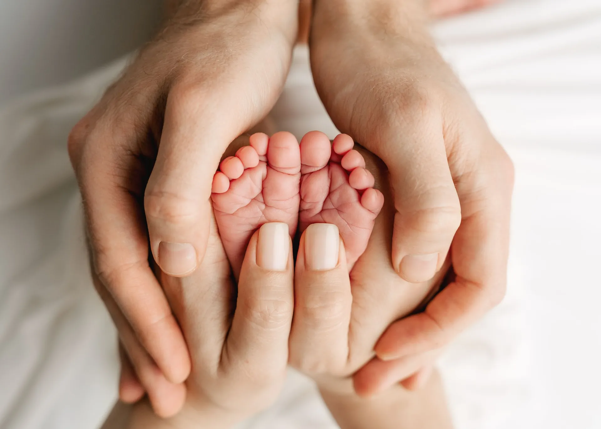 Tiny newborn baby feet cradled gently in adult hands - newborn details photography