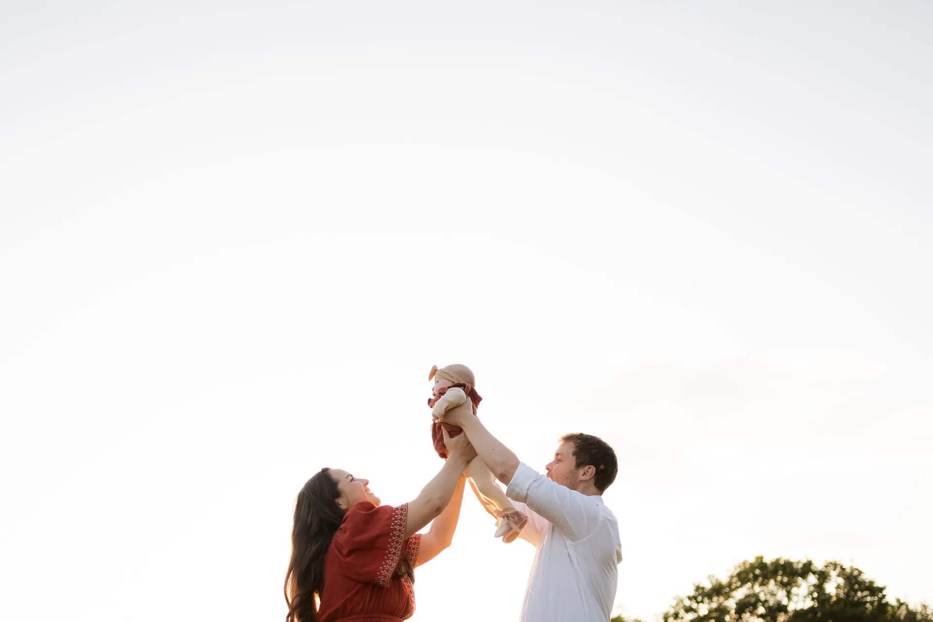 Parents playfully lift their baby in the air during sunset - family photographer Kingston upon Thames
